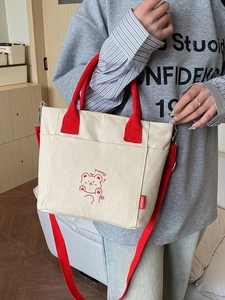 Canvas-Tragetasche mit roten Griffen und Bärenmotiv in wohnlicher Umgebung