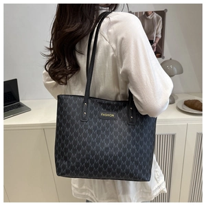 Detail of grey monogram tote bag with gold logo and shoulder strap on model