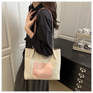 Detail of straw tote with pink faux leather pocket and stylish metal chain strap