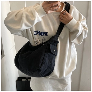 Detail of black canvas crescent bag with wide strap and silver metal buckle pocket