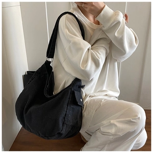 Detail of black canvas messenger bag with functional side pocket and silver button