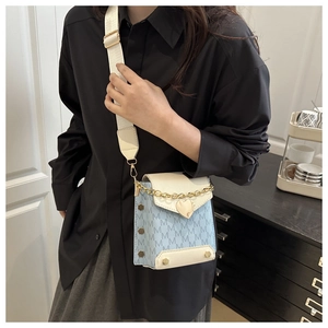 Detail of light blue crossbody bag with M-pattern jacquard and golden heart buckle