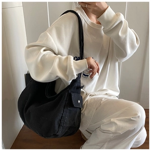 Detail showing side pocket with metal buckle on the large black canvas crossbody bag