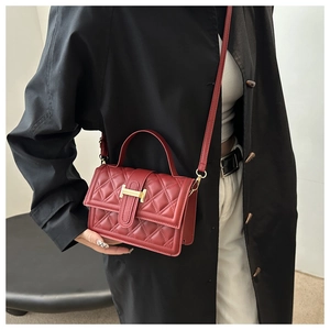 Nahaufnahme der roten gesteppten Handtasche mit goldenem H-Verschluss und Schulterriemen