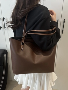 Large coffee brown faux leather tote bag shown from a side-view on model's shoulder