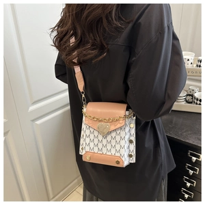 Detail of mini crossbody bag with heart lock, monogram pattern and gold chain strap