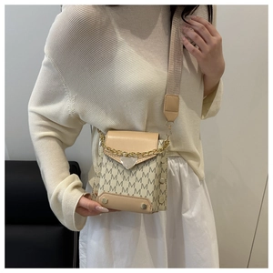 Detail of beige mini crossbody bag with M-pattern print, wide strap and gold hardware