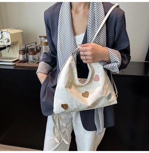 Detail der weißen Tragetasche mit bunten Herz-Aufnähern und Falten-Design im Lifestyle-Stil