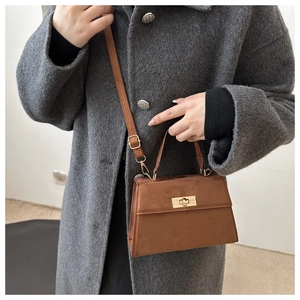 Brown suede crossbody bag with gold metal lock on a model in a grey tweed coat
