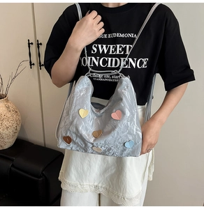 Detail der hellblauen Metallic-Tasche mit bunten Herz-Patches und Knitter-Struktur