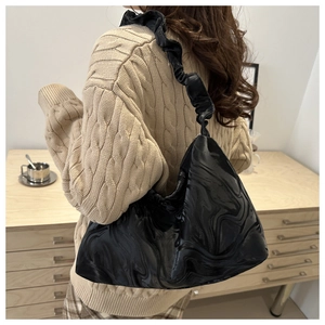 Detail der schwarzen glänzenden Hobo-Tasche mit Wasserwellenstruktur und Raffträger