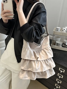 Beigefarbene Tragetasche mit mehrlagigen Rüschen und Schultergurt in einem Selfie präsentiert