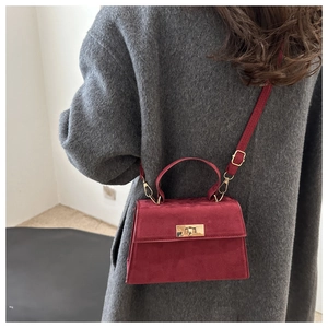 Close-up of a burgundy crossbody square bag with gold hardware and matte finish