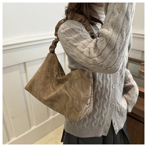Detail der khakifarbenen Tote Bag mit Marmormuster und gerüschtem Griff am Modell