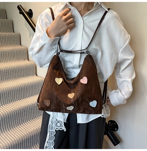 Detail der dunkelbraunen Tasche mit Knitteroptik und Herz-Patches an einem Frauenmodel