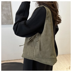 Détail d'un sac cabas en suédine verte avec un nœud décoratif sur le côté du sac à bandoulière