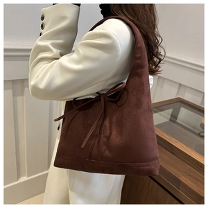 Detail of dark brown suede tote bag featuring a decorative side bow accent