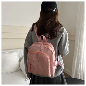 Detail of pink floral embroidery and dual zipper design on lightweight nylon backpack