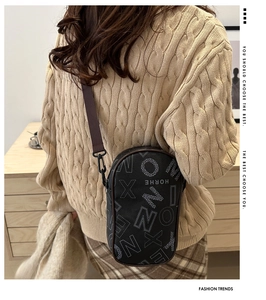 Close-up of printed crossbody phone bag with brown fabric strap and metal buckle