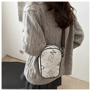 Detail view of white PU leather crossbody bag with graffiti print and wide shoulder strap