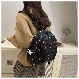 Detail of floral mini backpack showing black nylon fabric with pink flower patterns
