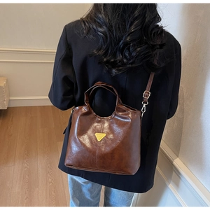 Detailed view of brown faux leather bucket bag texture and golden triangle hardware