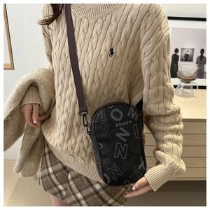 Close-up of black leather crossbody bag with white letter print on model outfit
