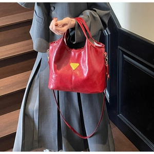 Close-up of shiny red leather bucket bag with a decorative gold triangle metal plate
