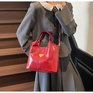 Detail of red wax leather bucket bag with gold triangle logo on a dark staircase