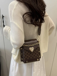 Brown crossbody phone bag with M-pattern print and heart-shaped metal buckle on model