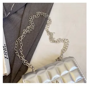 Gros plan du sac matelassé argenté avec doubles bandoulières en chaîne et texture chic