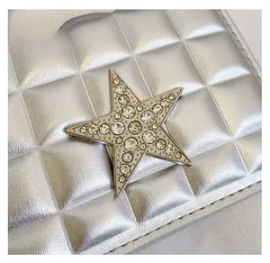 Détail de sac en cuir matelassé argenté avec boucle en forme d'étoile strassée