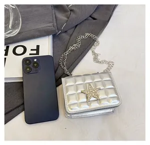 Mini sac bandoulière argenté matelassé avec étoile décorative à côté d'un mobile