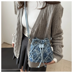 Chic quilted denim bucket bag with frayed fringe trim and adjustable shoulder strap
