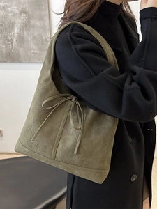 Sac fourre-tout en daim vert olive avec nœud décoratif porté à l'épaule sur manteau