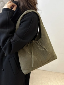 Cabas en daim vert olive avec nœud, porté par un mannequin en manteau noir d'hiver