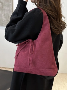 Sac cabas en daim bordeaux avec ruban porté à l'épaule par un mannequin