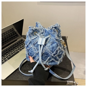 Detail of denim bucket bag showing quilted texture, frayed edges, and blue drawstring closure