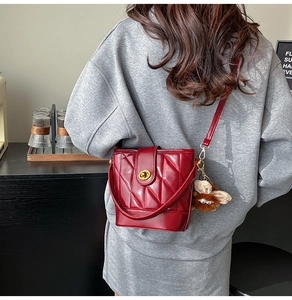 Détail du sac seau rouge matelassé avec boucle dorée et breloque chouette peluche