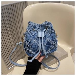 Detail of blue denim bucket bag featuring quilted frayed edges and leather drawstrings