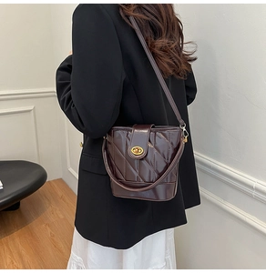 Détail d'un sac seau matelassé marron foncé avec fermoir doré et bandoulière élégante