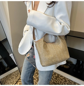 Detail of cross-woven straw bucket bag with brown leather straps and gold metal hardware