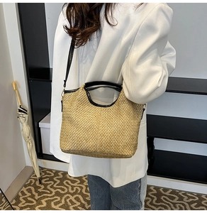 Detailed view of woven straw tote bag with black contrast trim and leather handle