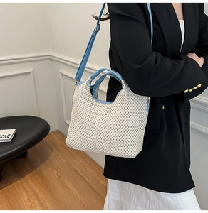 Detail of woven tote bag with light blue leather straps and adjustable gold buckle