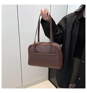 Detailed close-up of brown leather tote bag with large front pocket and top zipper