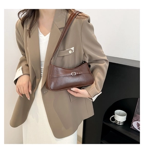 Brown vintage baguette bag with glossy leather finish and metal buckle on a shoulder strap