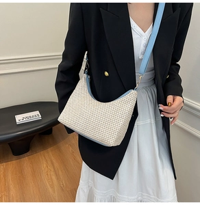 Close-up of woven straw tote bag with sky blue leather trim and detachable strap