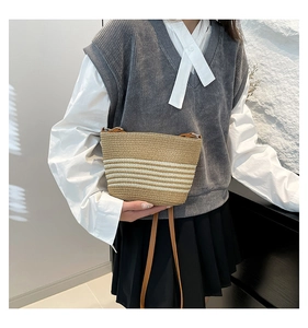 Detailed texture of hand-woven straw shoulder bag with white stripes and brown strap