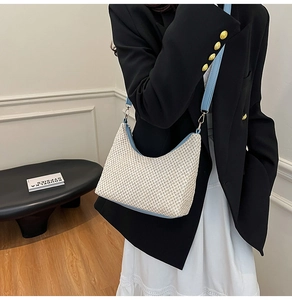 Detail of cream straw woven tote featuring light blue leather trim and gold metal hardware