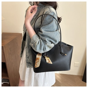 Detail of black leather tote bag with white contrast stitching and printed silk scarf handle